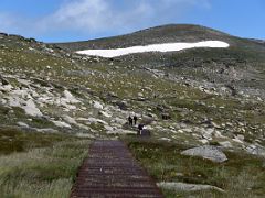 04A The Trail Zigzags Up Toward Cootapatamba Lookout With Mount Kosciuszko Summit Above The Snow On The Mount Kosciuszko Australia Hike
