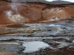 05A A steam vent in red soil caused by iron oxidation surrounded by mud pots and steaming hot water at Seltun Krysuvík geothermal area Reykjanes Peninsula Iceland