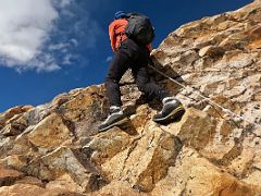 10B Climbing the traverse to the ridge on steep red rocky boulder slabs with hand ropes on the way to Lobuche East High Camp 5600m
