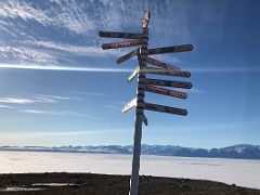 03A Distance Sign On A Hill With Bylot Island Across Eclipse Sound In Pond Inlet Mittimatalik Baffin Island Nunavut Canada For Floe Edge Adventure