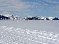 05A A Ski-doo Leads A Qamutiik Sled With Bylot Island Beyond On Day 3 Of Floe Edge Adventure Nunavut Canada